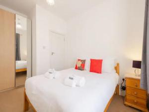 Un dormitorio con una cama blanca con dos animales de peluche. en Pass the Keys Spacious 3 Bed Flat Near Kings Cross and Camden, en Londres