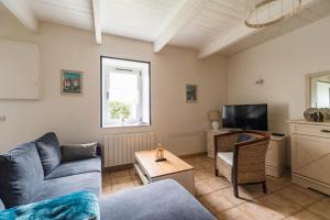 a living room with a couch and a tv at La Maison Bleue - 300m de la mer in Pleubian