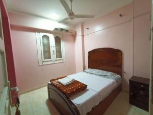 Schlafzimmer mit einem Bett mit einem Kopfteil aus Holz und einem Fenster in der Unterkunft david hostel in Assuan