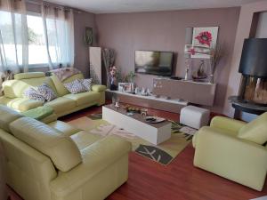 uma sala de estar com sofás amarelos e uma televisão em Maison Spacieuse et lumineuse avec piscine privée et chauffée em Pordic