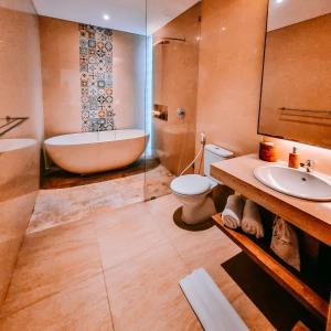 a bathroom with a tub and a toilet and a sink at Kahayana Suites Ubud in Ubud
