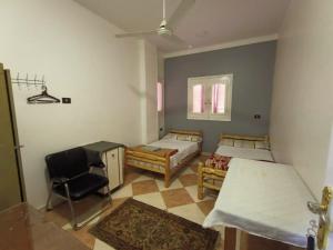 um quarto com duas camas e uma cadeira em david hostel em Aswan