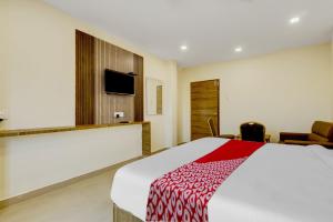 a hotel room with a bed and a tv at OYO Hotel Savitha's Grand in Vijayawāda