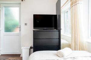 een slaapkamer met een flatscreen-tv op een zwart dressoir bij Earley Luxury Ensuite Room with private entrance in Reading