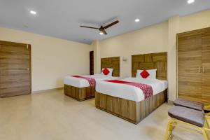 a bedroom with two beds and a ceiling fan at OYO Hotel Savitha's Grand in Vijayawāda