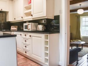 una cocina con armarios blancos y electrodomésticos blancos en Vintage Cottage, en Luddenden Foot