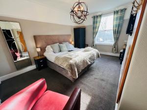 um quarto com uma cama grande e uma cadeira vermelha em Hedley House Hotel & Apartments em York