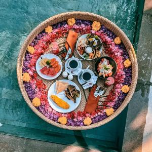 a plate of food on a table covered in flowers at Kahayana Suites Ubud in Ubud