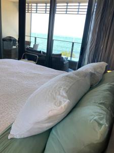 a bed with pillows on it with a view of the ocean at Mon Komo Seaview Privately Owned Apartment in Redcliffe