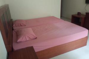 een bed met roze lakens en twee kussens erop bij OYO 93749 Aksana Homestay Syariah in Pekanbaru