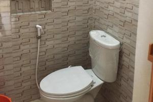 een badkamer met een wit toilet met een slang bij OYO 93749 Aksana Homestay Syariah in Pekanbaru