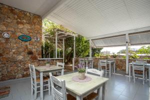 un patio con mesas y sillas y una pared de piedra. en Hotel Irini, en Livadia