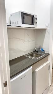 a kitchen with a sink and a microwave on a shelf at JARA HOME Malaga Centro in Málaga