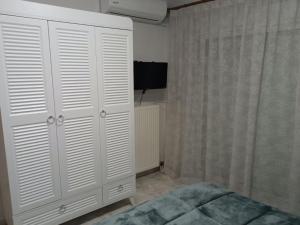 um quarto com um armário branco e uma televisão em J&B Home em Alexandroupoli