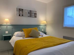 um quarto com uma cama com um cobertor amarelo em Le Petit Bois em Sainte-Marie-de-Ré