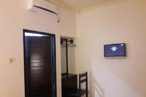 a room with a door and a television on the wall at OYO 93759 Yume Guest House in Midang