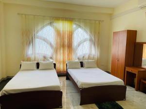 two beds in a room with a window at DreamCity Hotel in Kilinochchi
