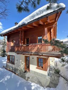 a log cabin with a deck in the snow at Chalet Cirmolo in Livigno