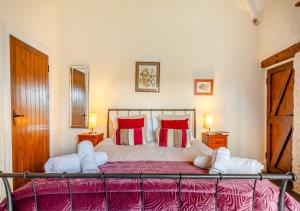 - une chambre dotée d'un grand lit avec des oreillers rouges et blancs dans l'établissement Oriel Cottage, à Bittadon