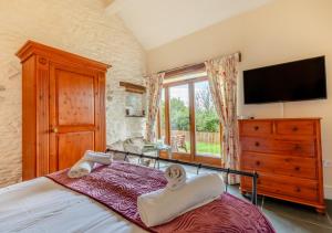 a bedroom with a bed with a dresser and a television at Oriel Cottage in Bittadon