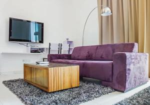 un sofá púrpura y una mesa de centro en la sala de estar. en Three Storey Garden Home at Bukit Gambir 18ppl, en Gelugor
