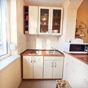 a kitchen with white cabinets and a sink and a microwave at Sunny Fort Apartments in Sunny Beach