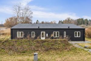 a black house with a black roof on a field at Brand New And Modern Summer House In Kulhuse in Jægerspris