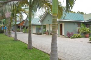 a group of palm trees in front of a house at 3 Degrees Hotel in Arusha