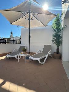 two chairs and a table and an umbrella on a roof at Soho Boutique Cádiz in Cádiz