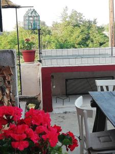 a view of a patio with red flowers and a table at Zoe's Yard family Summer House at Mon Repos in Anemómylos