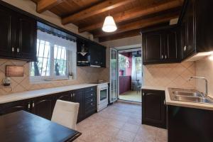 a kitchen with black cabinets and a sink at Zoe's Yard family Summer House at Mon Repos in Anemómylos