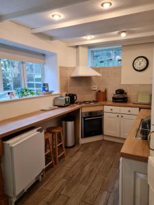 a kitchen with white cabinets and a clock on the wall at Anchorlea in Staithes