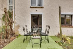 una mesa y sillas frente a un edificio en La "Marquise", Jardin et Parking Privatif en Guyancourt
