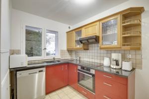 una cocina con armarios rojos y electrodomésticos blancos en La "Marquise", Jardin et Parking Privatif en Guyancourt
