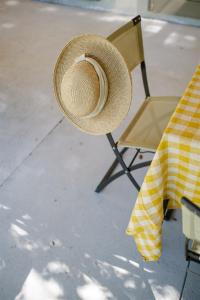 un chapeau en paille assis sur une chaise à côté d'une table dans l'établissement Le Répertoire - Maison Andréa, à Pernes-les-Fontaines