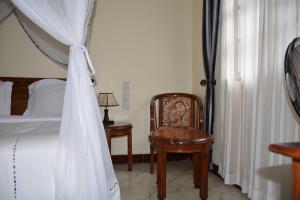 een slaapkamer met een hemelbed en een stoel bij 3 Degrees Hotel in Arusha