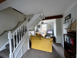 sala de estar con silla amarilla y escaleras en Tackleway privileged Sea Views Hastings old town whole house 3 beds en Hastings