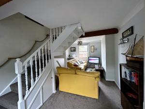 a living room with a yellow chair and stairs at Hastings Old Town Tackleway privileged Sea Views whole house 3 beds in Hastings