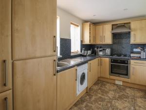 a kitchen with wooden cabinets and a washer and dryer at Penally in Llandysul