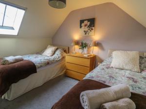 a bedroom with two beds and a dresser and a window at Penally in Llandysul