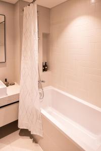een badkamer met een wit bad en een wastafel bij Tranquil 1BR Haven in the Heart of Vista Bliss - P1AB01 in Dubai