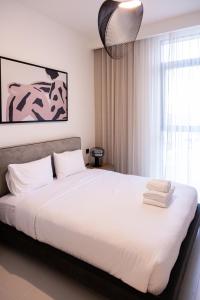 een slaapkamer met een groot bed met witte lakens bij Tranquil 1BR Haven in the Heart of Vista Bliss - P1AB01 in Dubai