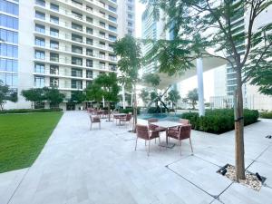 een patio met tafels en stoelen voor een gebouw bij Tranquil 1BR Haven in the Heart of Vista Bliss - P1AB01 in Dubai