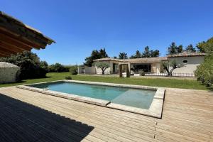 a swimming pool on a wooden deck in front of a house at Beautiful contemporary villa swimming pool and large garden in Berre-lʼÉtang