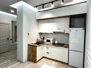 La cuisine est équipée de placards blancs et d'un réfrigérateur blanc. dans l'établissement apartments in Almaty, à Almaty