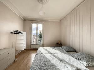 een witte slaapkamer met een bed en een raam bij "Le Bourgeois", Cœur Centre Ville, Paris in Le Vésinet