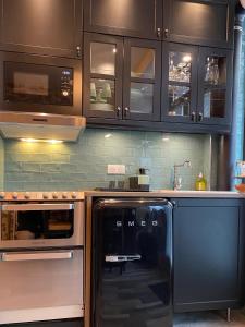 a kitchen with black cabinets and a black refrigerator at #SPA Wellness @ Paris 11ème in Paris +11 photos