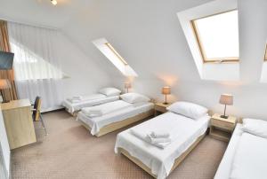 1 Schlafzimmer mit 3 Betten und einem Dachfenster in der Unterkunft Pokoje 4you Szczecin in Stettin