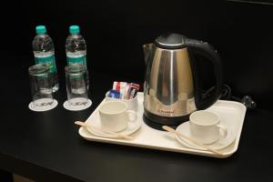a tea kettle and cups on a table with water bottles at HOTEL SR in Palani