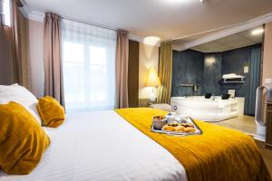 a hotel room with a bed with a tray of food on it at Grand Hôtel du Luxembourg & Spa in Bayeux +60 photos